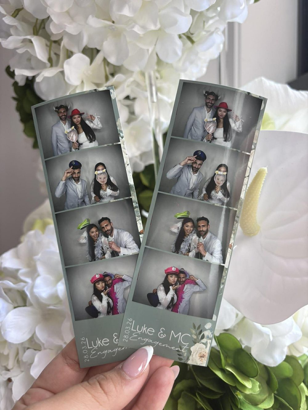 Two sage green photo strips printed with the couple's names, held in front of white hydrangeas